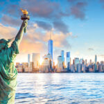 View of Statue of Liberty from back overlooking New York city skyline at sunset